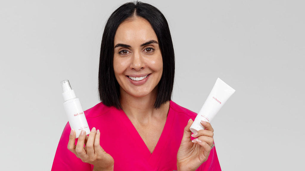 Seleren Founder Nurse Stef wearing pink scrubs holding two Seleren branded white bottles against a gray background