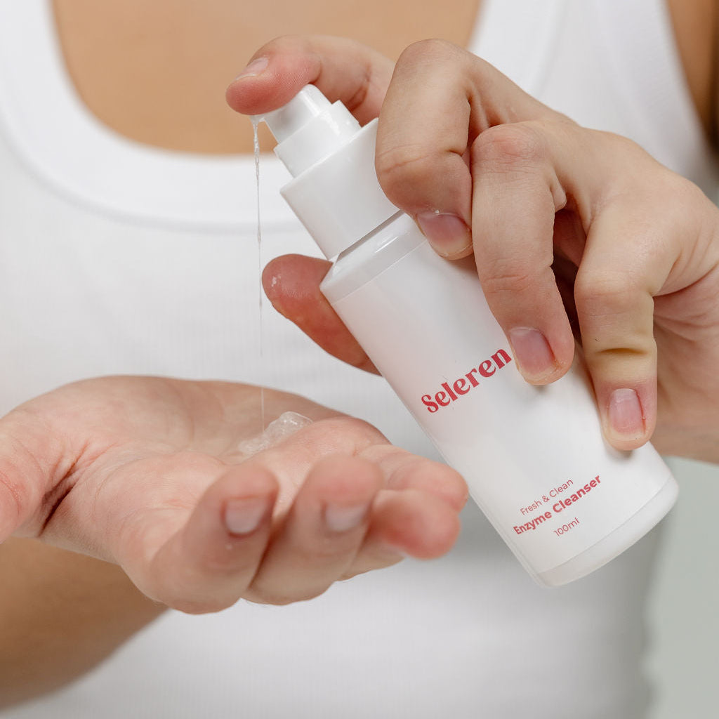 Person holding a white çleanser bottle labeled 'Seleren, against a neutral background.